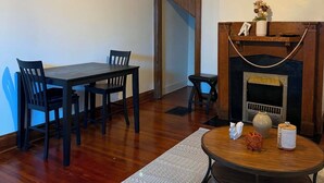 Un comedor con una mesa y sillas, un ventilador de techo, una chimenea y una mesa redonda con cojín.