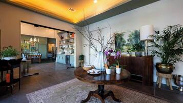 Um interior moderno com uma mesa de madeira redonda, uma área de refeições e uma cozinha visível através de uma porta aberta.