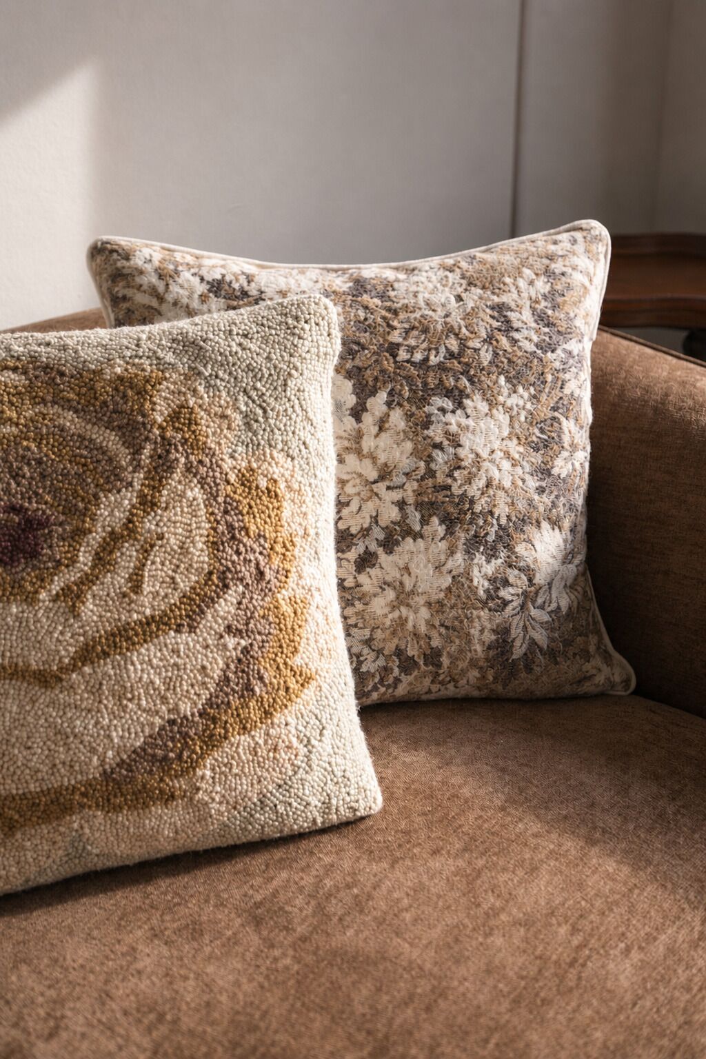 Two square cushions on a brown sofa.