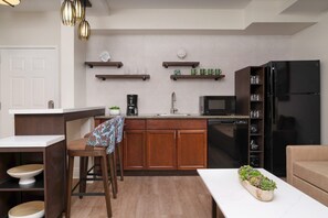 Una cocina moderna con armarios de madera, un refrigerador negro, un microondas y una cafetera.