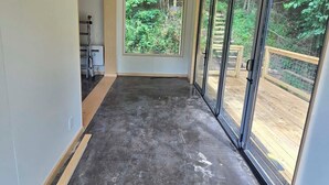 A spacious room with a large window, a ceiling with recessed lighting, and a dark floor.