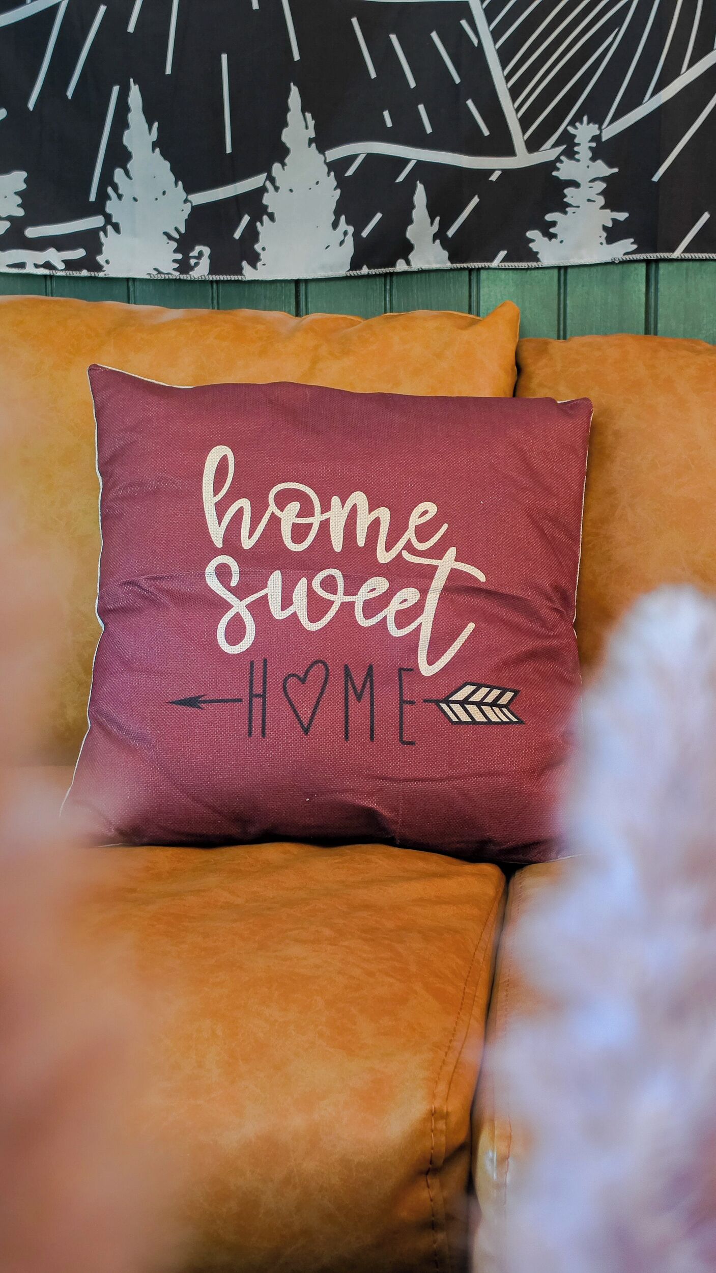 Un coussin orné de l’inscription « chez soi, quel bonheur » sur un canapé.