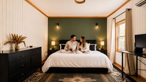 A bedroom with a bed, bedside tables, a dresser, a TV, and a window. - Onyx at Nada - Your Escape to Nada Tunnel (Stanton)
