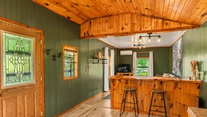 A kitchen with wooden cabinets, a bar area with stools, and a large window. - Onyx at Nada - Your Escape to Nada Tunnel (Stanton)