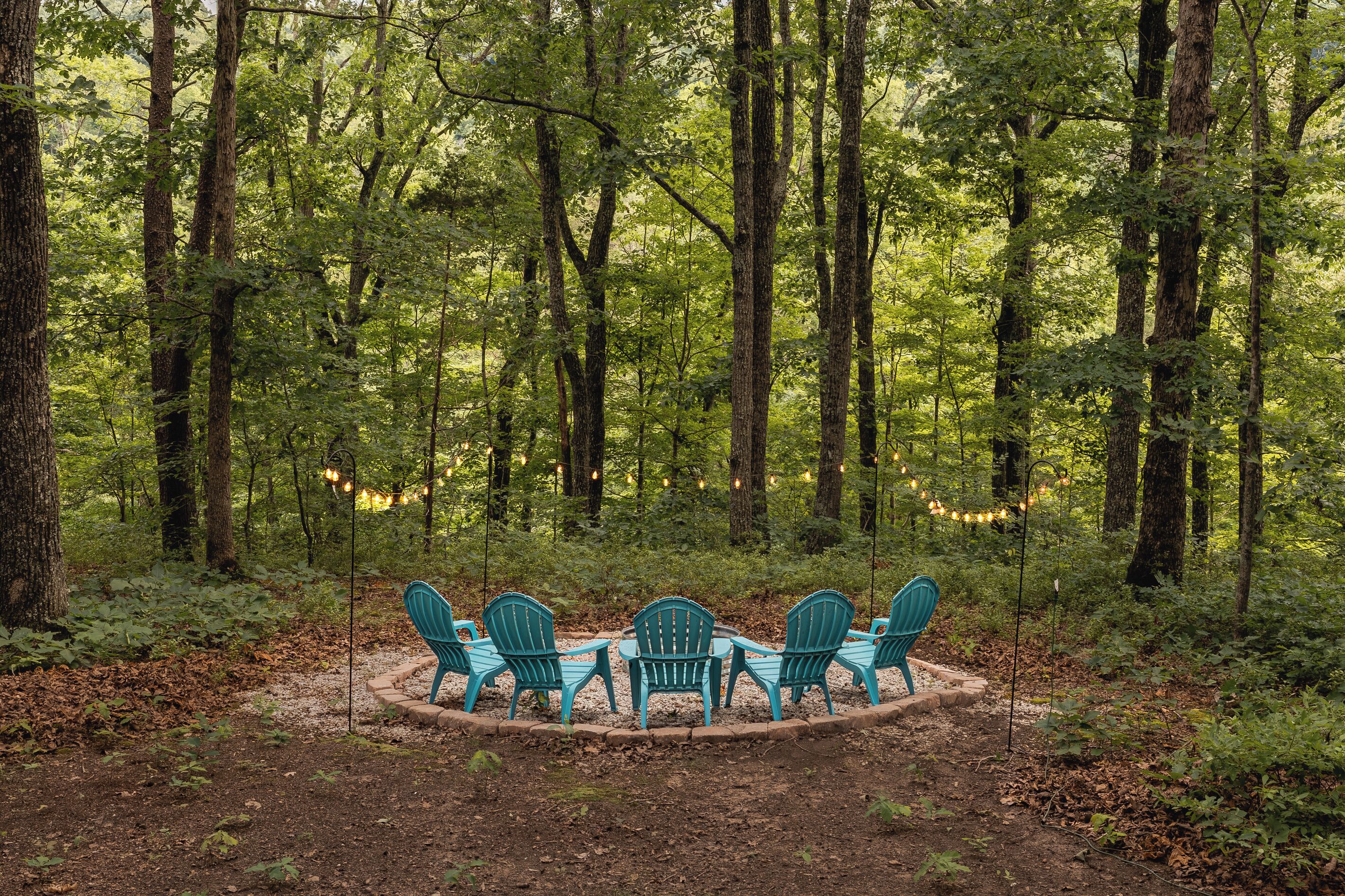 A forest with a circular seating area featuring chairs and a table.