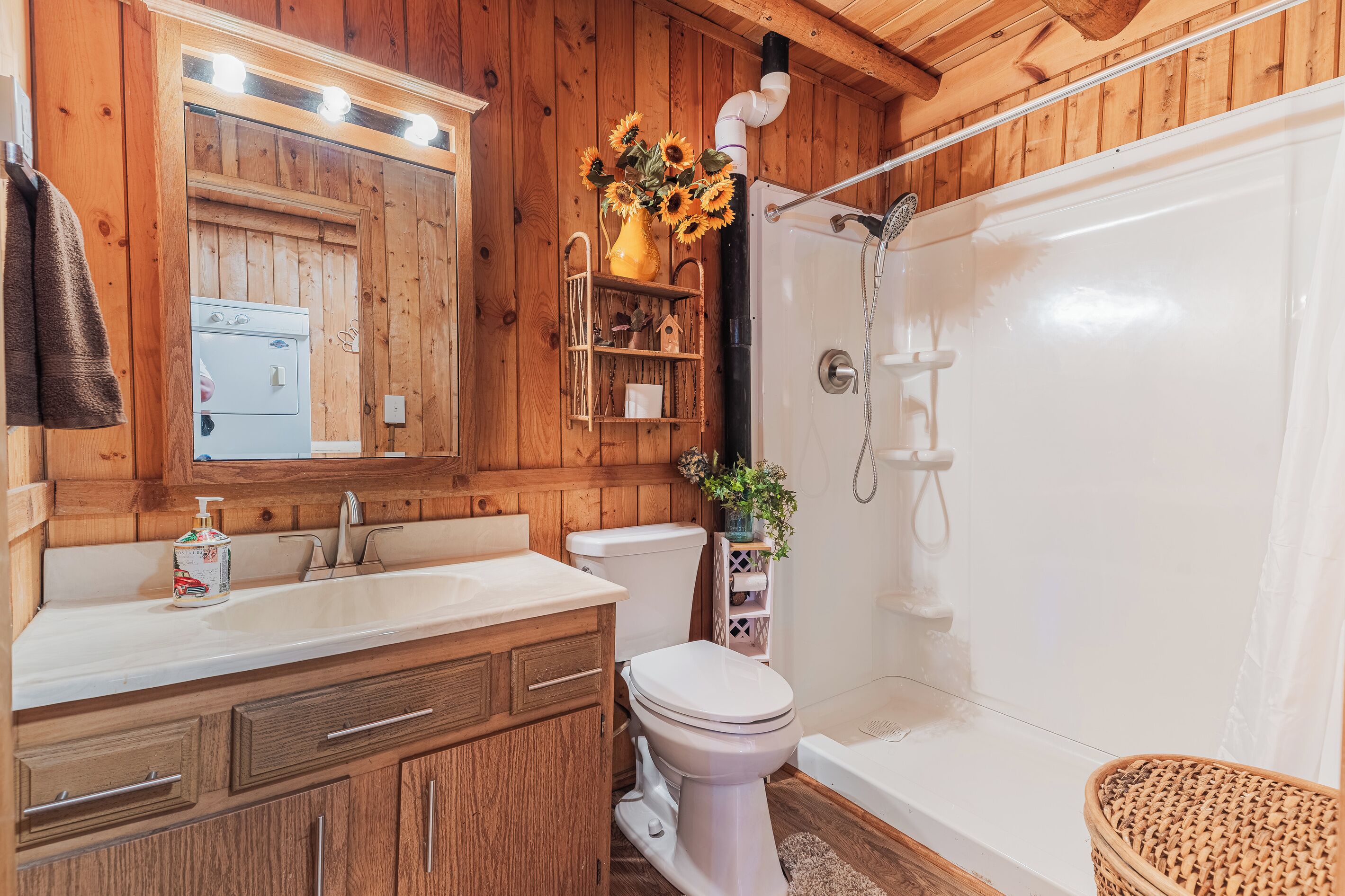 A wooden cabin bathroom with a sink, toilet, and shower.