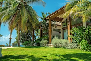 Un bâtiment moderne doté de grandes fenêtres, entouré d’une végétation luxuriante et de palmiers.