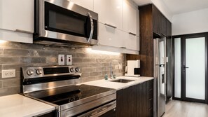 A modern kitchen with stainless steel appliances, a built-in oven, microwave, and a coffee machine. - Bessa Beachfront Ocean Suite | 2BR | Oracabessa ➠ U66 (Oracabessa)