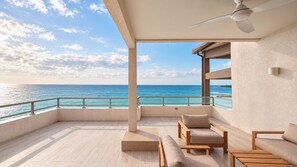 A balcony with a view of the ocean, wooden furniture, and a ceiling fan. - Bessa Beachfront Ocean Suite | 2BR | Oracabessa ➠ U66 (Oracabessa)