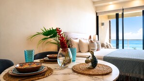Ein modernes Zimmer mit Meerblick, ein Esstisch mit Geschirr und eine Vase mit Blumen, sowie eine Couch mit Kissen.