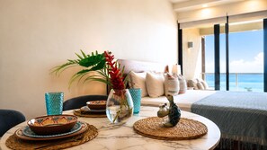Ein modernes Zimmer mit Meerblick, ein Esstisch mit Geschirr und eine Vase mit Blumen, sowie eine Couch mit Kissen.