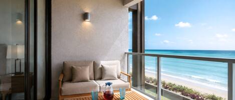 Un balcon avec un canapé et une table, donnant sur une plage.