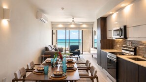 A modern kitchen with a view of the ocean, a dining area with a table set for two, and a seating area with a view.