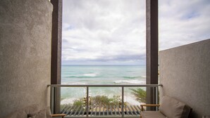 Een balkon met uitzicht op de oceaan, twee banken en een houten tafel.