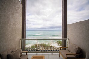 Ein Balkon mit Blick auf das Meer, zwei Sofas und ein Holztisch.
