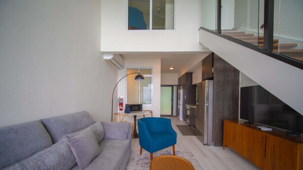 Een moderne woonkamer met een grijze bank, een blauwe fauteuil en een houten bijzettafeltje.