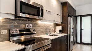 Une cuisine moderne équipée d’appareils électroménagers en acier inoxydable, d’un four encastré, d’un four à micro-ondes et d’une machine à café.