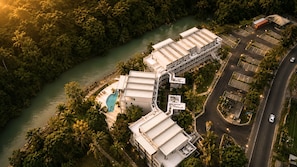 An aerial view of a hotel complex with multiple buildings, a swimming pool, and a river. - Bessa | Beachfront Suite | 2BR, Seaside Pool ➠ U86 (Oracabessa)