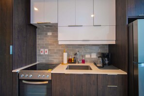 A modern kitchen with dark wood cabinets, a white countertop, a built-in oven, and a stainless steel refrigerator. - Bessa | Beachfront 2BR Loft, Private Roof Terrace ➠ U80 (Oracabessa)