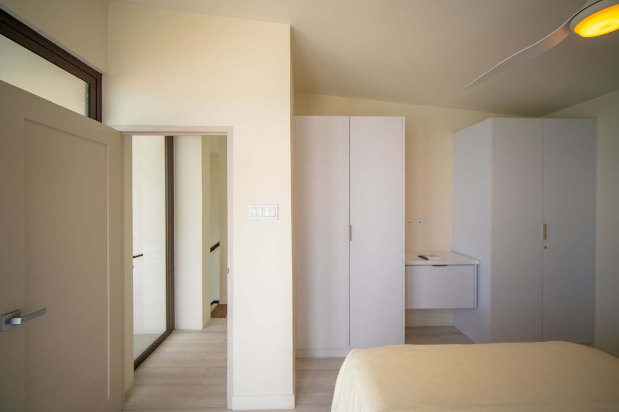 A hotel room with a bed, a wardrobe, a mirror, and a door leading to another room.