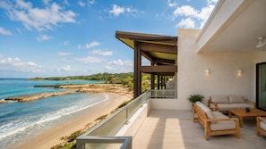 A balcony with a view of a beach and ocean.