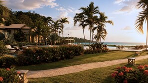A resort with a pool, palm trees, and a view of the ocean.