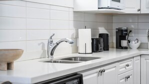 A modern kitchen with white cabinets, a stainless steel sink, a coffee maker, and a microwave. - Beautiful 2 bedroom 1 bathrom (Burnaby)