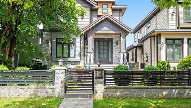 A two-story house with a stone facade, a front porch, and a gated driveway. - Beautiful 2 bedroom 1 bathrom (Burnaby)