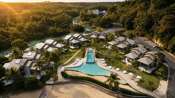 A resort with multiple bungalow-style accommodations, a central swimming pool, and a beach area.