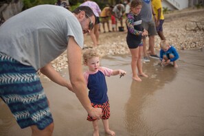 A beach scene with people, including a child holding a seashell.