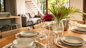 A dining table set with plates, glasses, and a vase with red flowers.