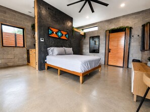 A modern bedroom with a large bed, a wooden desk, and a view of the outdoors. - LA ROCA - Boutique Fayetteville Studio (Fayetteville)