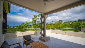 A covered outdoor area with a ceiling fan, a wooden table, and two chairs. - Bessa | Riverfront 2BR | River, Sea & Pool ➠ U4 (Oracabessa)