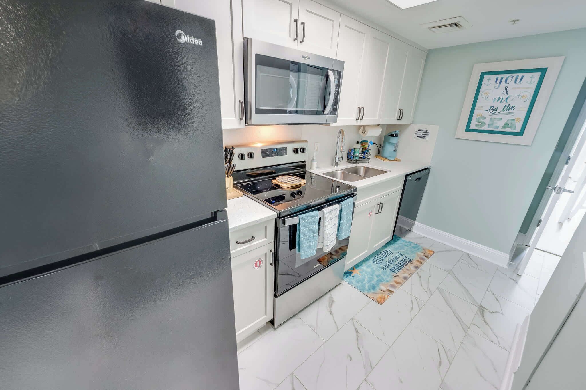 A modern kitchen with a refrigerator, microwave, stove, and sink.
