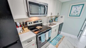 Una cocina moderna con microondas, estufa y lavamanos.