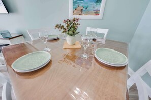 Una mesa de comedor con cuatro platos, dos copas de vino y un florero con flores.