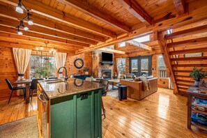 Ein Holzblockhaus-Interieur mit Essbereich, Küche, Wohnzimmer und Kamin.