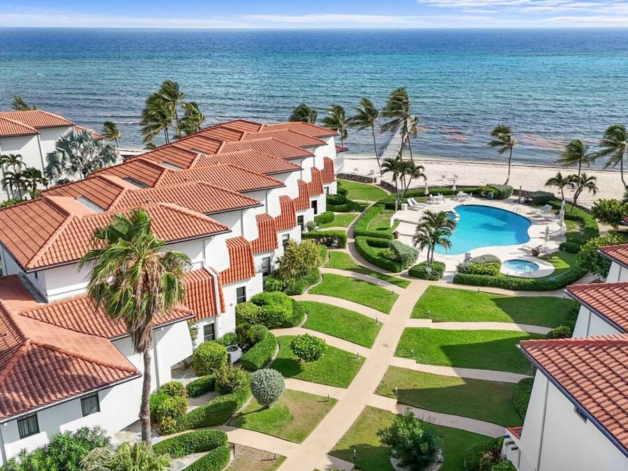 A resort with a swimming pool, palm trees, and a view of the ocean.