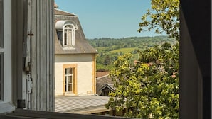 Une maison avec un toit en pente, une fenêtre et une vue sur un paysage verdoyant.