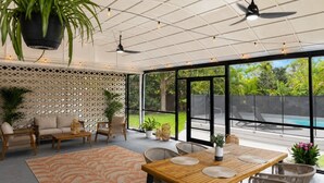 Un espacio al aire libre cubierto con mesa, sillas, un sofá y un ventilador de techo.