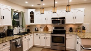 Una cocina moderna con armarios blancos, electrodomésticos de acero inoxidable y encimera de granito.