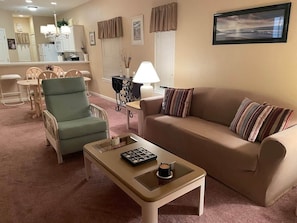 Una sala de estar con sofá, sillón, mesa de centro y comedor con sillas y una mesa.