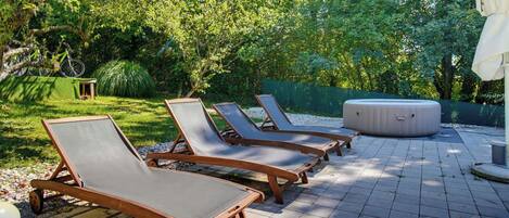 A patio with sun loungers and a hot tub.