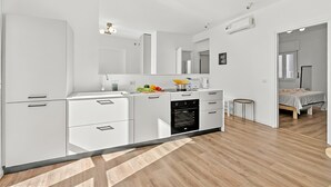 Eine moderne Küche mit weißen Schränken, einem eingebauten Ofen und einem Essbereich mit einem kleinen runden Tisch.