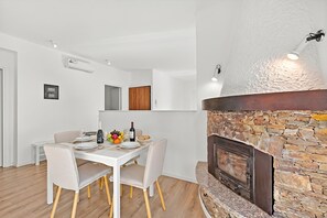 A modern dining area with a stone fireplace, white walls, and a wooden floor. - Quadrifoglio Stresa Hill with A/C and Sunny Balcony, Stresa, Italy (Stresa)