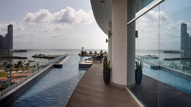 Une piscine d’hôtel moderne offrant une vue sur la mer et le paysage urbain.