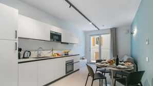Cozinha moderna com armários brancos, micro-ondas e área de jantar com mesa posta para dois.