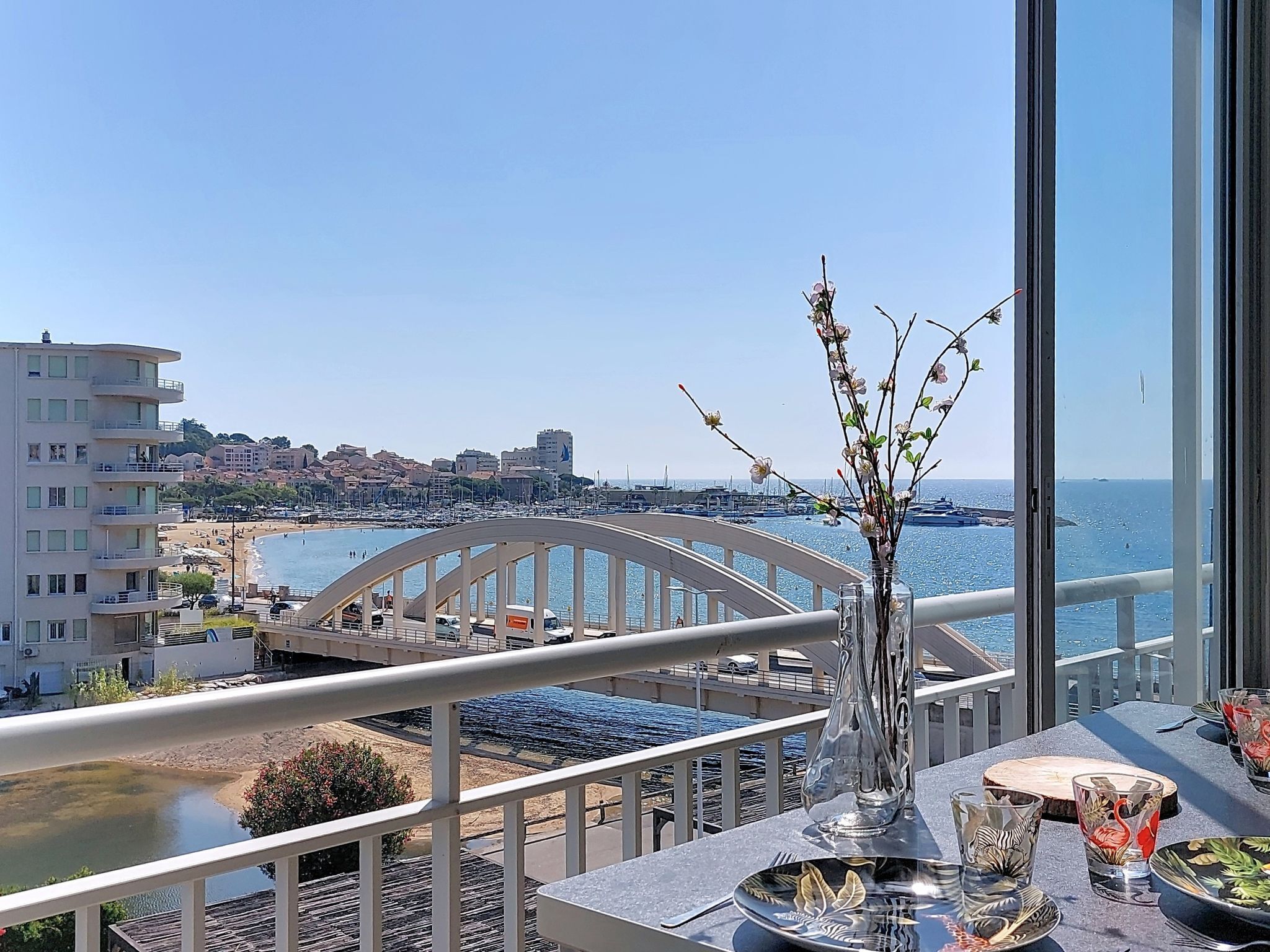 Een balkon met uitzicht op zee, een brug en gebouwen op de achtergrond.