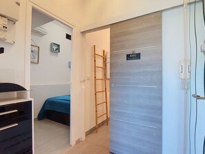 A room with a bed, a wardrobe, a door with a sign, and a wall-mounted air conditioner. - Bel Horizon 2 by Interhome (Sainte Maxime)