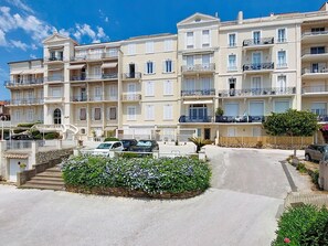 Ein mehrstöckiges Hotel mit Balkonen, einem Innenhof und einem Parkplatz.